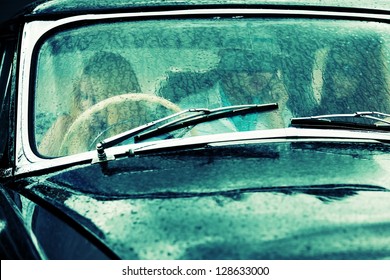 Young people driving retro car in the rain