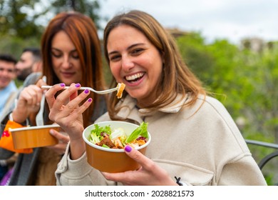 Young People Eating Take Away Food At City Park