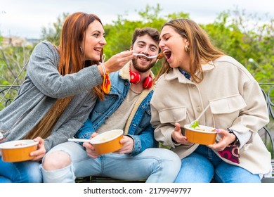 Young people eating take away food at city park - Happy young friends eating takeaway food outdoor in the city – young people eating fast food from takeaway paper bowl – group of friends eating togeth - Powered by Shutterstock