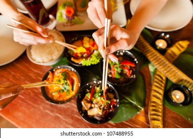 Young People Eating In A Thai Restaurant, They Eating With Chopsticks, Close-up On Hands And Food