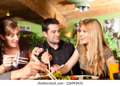 Young People Eating In A Thai Restaurant, They Eating With Chopsticks