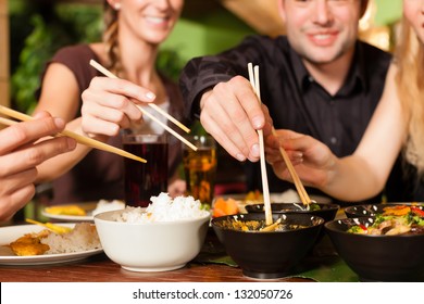 Young people eating in a Thai restaurant, they eating with chopsticks