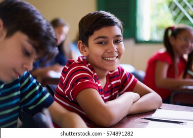 Young people and education. Group of hispanic students in class at school during lesson. Happy boy smiling and sitting at desk