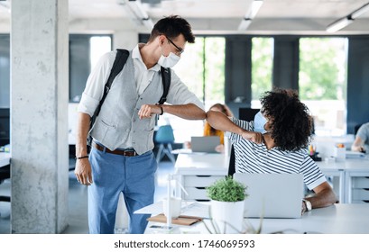 Young People With Face Masks Back At Work In Office After Lockdown, Greeting.