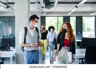 Young people with face masks back at work in office after lockdown, talking. - Powered by Shutterstock