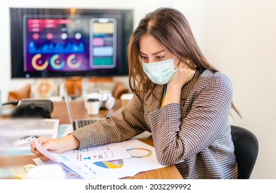 Young People With Face Masks Back At Work In Office After Lockdown.Asian Small Business Startup Multiracial Brainstorm Meeting With Laptop And Chart Paper Everyone Mask For Covid19 Protection Corona.