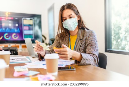 Young People With Face Masks Back At Work In Office After Lockdown.Asian Small Business Startup Multiracial Brainstorm Meeting With Laptop And Chart Paper Everyone Mask For Covid19 Protection Corona.