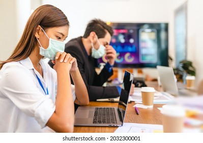 Young People With Face Masks Back At Work In Office After Lockdown.Asian Small Business Startup  Meeting With Laptop And Chart Paper Everyone Mask For Covid19 Protection Corona.