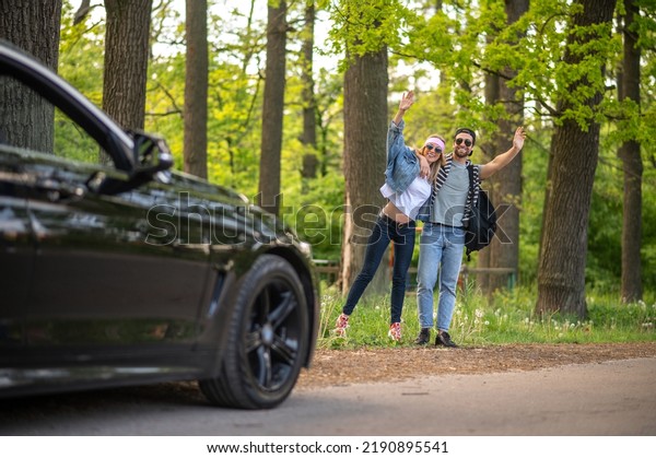 Young people in the forest stopping the car and\
looking joyful