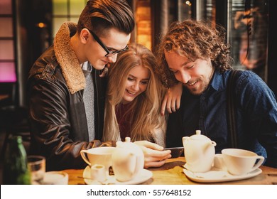 Young people - Friends having fun, looking at a phone. - Shutterstock ID 557648152