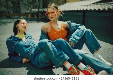 Young people, girls wearing denim clothes and and colorful accessories. Chilling on urban rooftop on a daytime. Concept of 90s, fashion, youth culture, old-style trends - Powered by Shutterstock