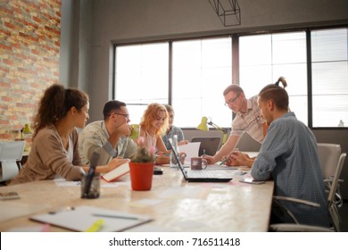Los grupos de jóvenes en las oficinas modernas tienen reuniones de equipo y tormentas de ideas, mientras algunos trabajan en laptops