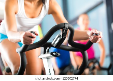 Young People - group of women and men - doing sport biking in the gym for fitness