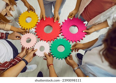 Young people hands connect multy colored cogwheels to make gear. Symbol of collaboration, teamwork, team building, connection, partnership and integration. Business cooperation concept. - Powered by Shutterstock