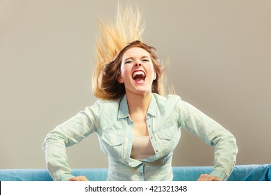 Young People Happiness Concept. Fashionable Girl Wearing Denim Relaxing On Blue Couch Wind In Hair Face Expression