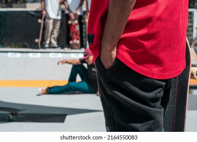 Young People Having Fun While Training At The Skatepark. Skateboarding Event With A Crowd And Someone Falling At The Background.