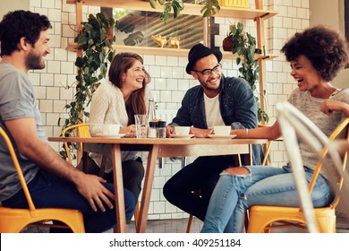 Young People Having A Great Time In Cafe. Friends Smiling And Sitting In A Coffee Shop, Drinking Coffee And Enjoying Together.