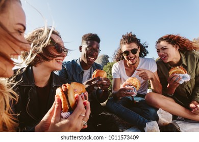 Young people having summer picnic and eating together sitting on mountain top. Happy friends on mountain top having a picnic on a summer day.