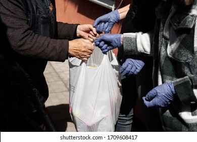 Young People Helping Old Woman With Products. Hands In Gloves, Help During Quarantine 
Through Coronavirus Infection. Social Help And Support. Volunteering. Taking Care Of Loved Ones. Charity.