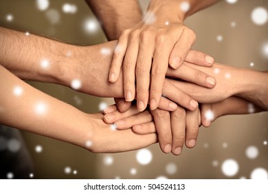 Young people holding hands together, closeup. Snowy effect, Christmas concept. - Shutterstock ID 504524113