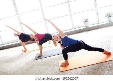 Young people holding triangle pose in a yoga class