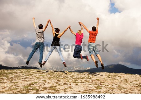young people jumping holding hands on nature. 
teamwork concept.
