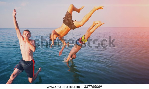 夏の遠足の日に 若者が海の中を飛び跳ねる 幸せな狂った友達が 帆船から海に飛び込む 熱帯の休暇 若者 旅行 楽しいコンセプト水中の幸せな人々のグループ の写真素材 今すぐ編集