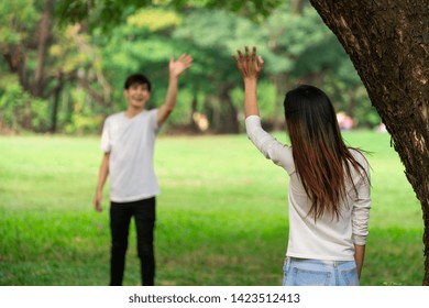 Young People, Man And Woman Greeting Or Saying Goodbye By Waving Hands In The Park.