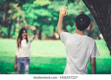 Young People, Man And Woman Greeting Or Saying Goodbye By Waving Hands In The Park.