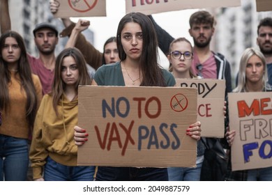Young people marching with signs with novax slogans  - concept of young people protesting against the mandatory vaccine and vax pass