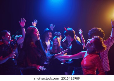 Young people, men and women dressed in themed costumes, with creepy makeup, attending Halloween party at nightclub, dancing, laughing. Concept of Halloween, holiday, party, leisure