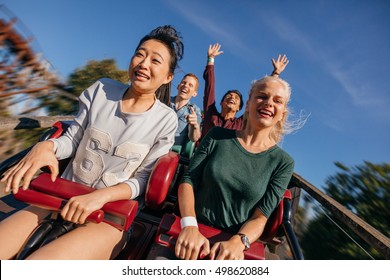 Young people on a thrilling roller coaster ride. Group of friends having fun at amusement park. - Shutterstock ID 498620884