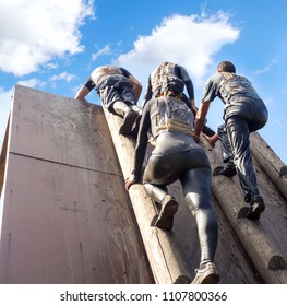 Young people pass the obstacle course. Mud race runners. Rise to the obstacle. Teamwork. - Powered by Shutterstock