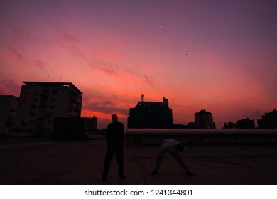 Young people practicing parkour on the rooftop of the building on the sunrise - Powered by Shutterstock