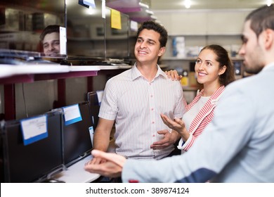 Young People Purchasing Flat Screen Television Set In Electronics Store 