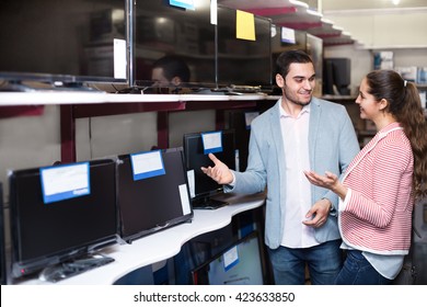 Young people purchasing a flat screen television set at electronics store 