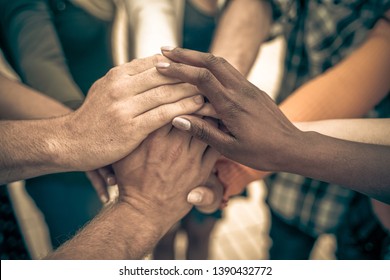 Young people putting their hands together. Friends with stack of hands showing unity and teamwork – Image - Shutterstock ID 1390432772