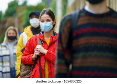 Young People Queuing Outdoors In Town. Coronavirus And Safe Distance Concept.