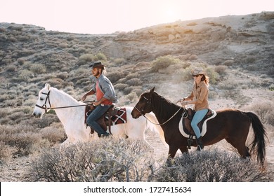 Young People Riding Horses Doing Excursion At Sunset - Wild Couple Having Fun In Equestrian Tour  - Training, Culture, Passion, Healthy Lifestyle, Sport Concept