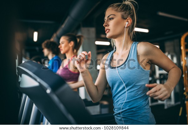 Young\
people running on a treadmill in health\
club.