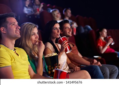 Young People Sitting In Multiplex Movie Theater, Watching Movie, Eating Popcorn.