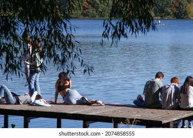 Young People Sitting On The Edge Of A Pier. Sitting Pier Images. Relaxation by the Lake.