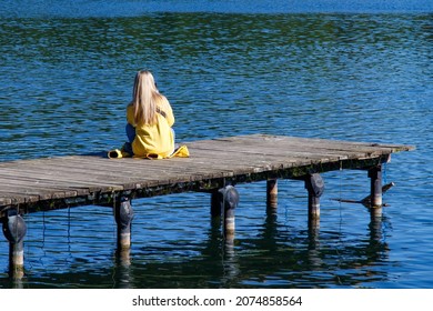 Young People Sitting On The Edge Of A Pier. Sitting Pier Images. The girl sits alone. Relaxation