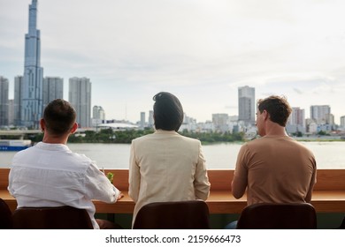 Young People Sitting At Rooftop Bar Counter, Drinking Cocktails And Enjoying Beautiful City View