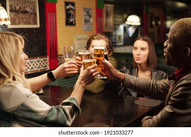 Young people sitting at the table drinking beer during their meeting in the pub