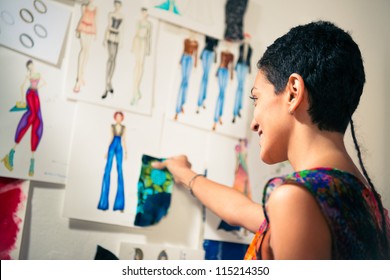 Young people and small business, hispanic woman at work as fashion designer and tailor, looking at sketches of new collection in atelier - Powered by Shutterstock