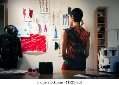 Young people and small business, hispanic woman at work as fashion designer and tailor, looking at sketches of new collection in atelier