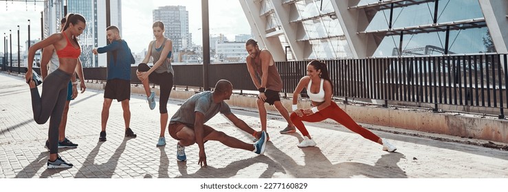 Young people in sports clothing warming up before outdoors group training - Powered by Shutterstock