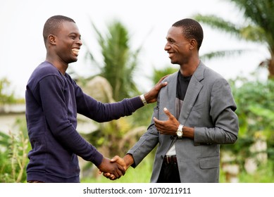 Young People Standing In Grass Greet Each Other Laughing.