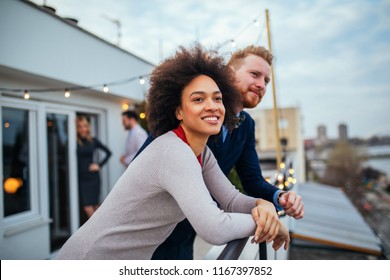 Young people standing and laughing on the rooftop - Shutterstock ID 1167397852